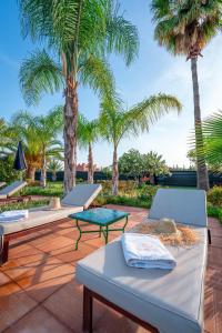 a row of beds on a patio with palm trees at Palais les sources de l'atlas, Padel & spa in Marrakesh
