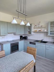 a kitchen with blue cabinets and a table with chairs at Ferienwohnung Waldblick mit Balkon in Sebnitz