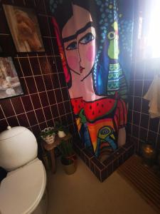 a bathroom with a painting on the wall next to a toilet at Den gamle smedie in Holbæk +16 photos