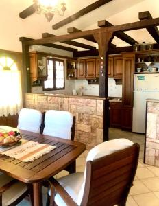 a kitchen with a wooden table and white chairs at Petrothalassa View in Kranidi