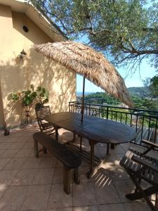 uma mesa de piquenique com um guarda-chuva de palha no pátio em Casa Artigena em Rapallo