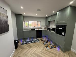 a kitchen with green cabinets and a wooden floor at Luxurious 3 bedrooms flat near New Cross,Wolverhampton No Parties or events in Wednesfield
