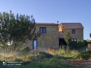 an old stone house with a tree in front of it at Quinta Damigo in Seia