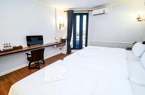 1 Schlafzimmer mit 2 Betten und einem Schreibtisch mit einem TV in der Unterkunft Asia Mahanakhorn Travel in Bangkok