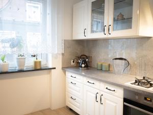 a kitchen with white cabinets and a window at Apartament Vikicentrum in Bolesławiec