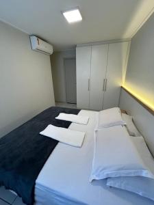 sypialnia z dużym białym łóżkiem z białymi szafkami w obiekcie Apartamento Beira Mar Pajuçara w mieście Maceió +65 zdjęć