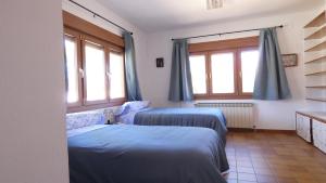 two beds in a room with two windows at Casa Rural en Valmuel El Arquero in Valmuel