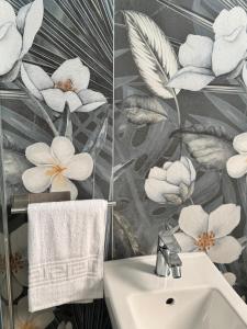 a bathroom with a white sink and flowers on the wall at Cavour Luxury Rooms Catanzaro in Catanzaro +83 photos