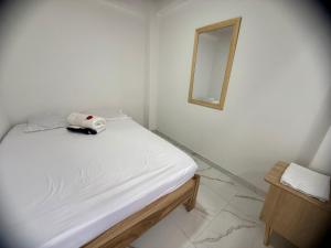 um quarto branco com uma cama e um espelho em Apartamento Piso 1 Casa 6 Hotel Atlantis em Líbano