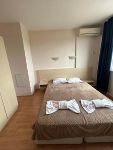 a bedroom with a bed with two white bows at Harmony Hills Tomovi Apartment F45 in Rogachevo +3 photos
