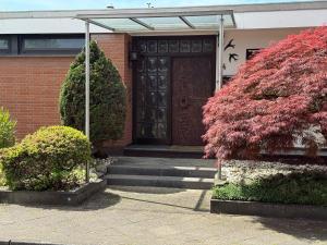 a brick building with a wooden door and some bushes at Superior Haus 120 qm mit Garten in Düsseldorf