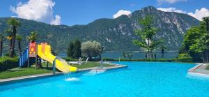 a pool with a slide in the water with a mountain at Panoramic View Frontal Apartment in Bissone