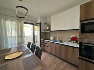a kitchen with a wooden table and a dining room at Aurela Apartment 1 in Lezhë
