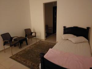 ein Schlafzimmer mit einem Bett und zwei Stühlen und einem Teppich in der Unterkunft 3-Bedroom Furnished Apartment - Golden Beach Resort, North Coast in Dawwār Ibrāhīm Abū Shunaywīr
