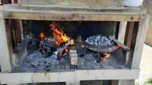 a fire in a stone oven with a pot and aauldron at Seosko domaćinstvo STAREVINA in Nikšić