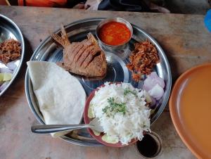 a plate of food with rice and meat and sauce at Wantara resort in Diveagar