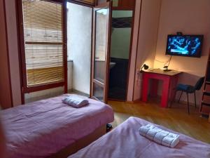 una stanza con due letti, una scrivania e una televisione di Villa Vanila a Kutaisi
