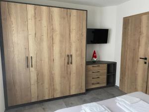 a bedroom with two wooden cabinets and a tv at Guest House Cemin in Predazzo