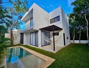 a white house with a swimming pool in front of it at Beatiful House 3BR private pool Gated community in Chacalal