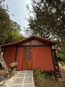 a small red house with a large wooden door at Cabana Zen - Sítio Gaia Magia in Miguel Pereira