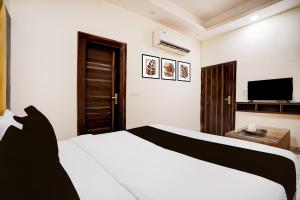 a bedroom with a white bed and a flat screen tv at Hotel O Paradise in Ghaziabad