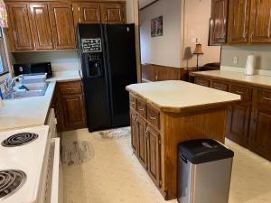 a kitchen with a black refrigerator and wooden cabinets at Eureka Springs Country 4bd 2ba Full House - Enjoy a Country Retreat near Beaver Lake and Dam, the White River and Eureka Springs Area in Eureka Springs +7 photos