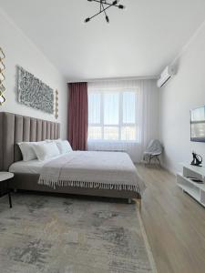 ein weißes Schlafzimmer mit einem großen Bett und einem Fenster in der Unterkunft Кок-Жайлау 1-комнатная за Хан Шатыром in Astana + 9 Fotos
