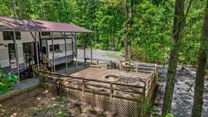 an rv parked next to a forest with a wooden deck at Happy Glamper RV at Haven of Hope near Little River Canyon National Preserve in Fort Payne