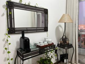 a mirror on a wall next to a table with a lamp at Cobertura 403 Braga · Complete apartment with private pool Cabo Frio in Cabo Frio