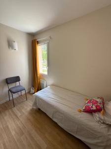 a bedroom with a bed and a chair and a window at Village Vacances de Bretou in Eymet +23 photos