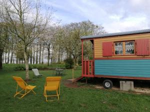 a tiny house and two chairs in a yard at Roulotte Gabi in Rouville