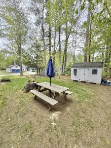 a picnic table with an umbrella in a field at KENDALL COTTAGE LIMIT 6 villa in North Sebago