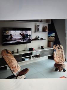a living room with two chairs and a flat screen tv at Maison familiale in Plouzané