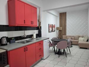 a kitchen with red cabinets and a living room at Philippos Apartments in Acharavi