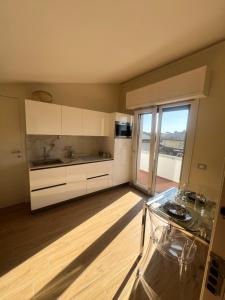 トッレ・デル・ラーゴ・プッチーニにあるLa Casinaの白いキャビネットとガラスのテーブル付きのキッチン +5枚の写真