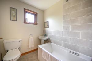 a bathroom with a tub and a toilet and a sink at The Wee Gem - 9 Milking Hill Park in Stornoway +19 photos