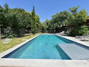 ein Swimmingpool mit blauem Wasser in einem Hof in der Unterkunft Croassecorbeau Maison de Famille au pied du Ventoux in Malaucène