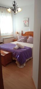 a bedroom with a bed with purple sheets and a window at La Pérgola Apartamento Sierra de Albarracín Planta baja y Garaje in Bronchales