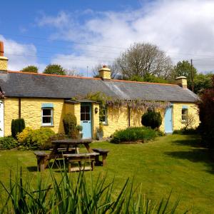 ein gelbes Cottage mit einem Picknicktisch davor in der Unterkunft Charming Welsh Cottage in Johnston
