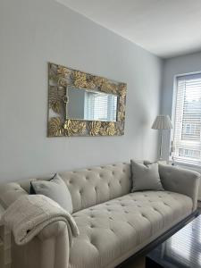 a living room with a couch and a mirror at Modern One Bedroom Apartment, Sloane Square in London
