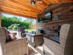 a patio with wicker chairs and a television on a wooden wall at Luxury At Meadowbrook, Pool Home, Fire Pit, Fort in Valdosta