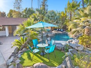 a table and chairs with an umbrella next to a pool at NEW LUXURY ESTATE - Sleeps 22 - Saltwater Pool, Spa, Waterfall With Cave Grotto! in Vista