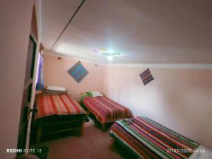 a small room with two beds and a ceiling at Amantaní Elisa's lodge Puno in Puno
