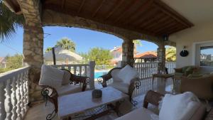 a porch with chairs and a table and a pool at Villa Belle ,Fethiye in Fethiye +43 photos