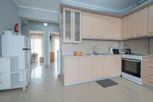 a kitchen with white cabinets and a white refrigerator at M&P Apartment by RentalsPro - Nea Moudania Halkidiki in Nea Moudania