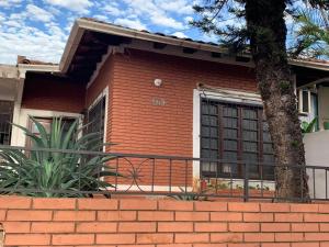 una casa de ladrillo rojo con un árbol y una valla en Lapacho Roga, en Asunción