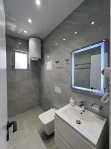 a bathroom with a sink and a toilet and a mirror at Vila ENSO in Berat