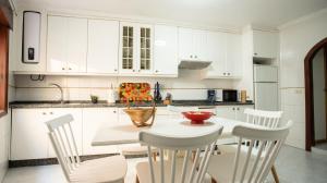 a kitchen with white cabinets and a white table and chairs at Casa Marinera en A Guarda in A Guarda