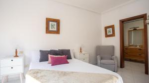 a bedroom with a white bed with a pink pillow at Casa Marinera en A Guarda in A Guarda