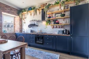 cocina con armarios azules y pared de ladrillo en The Nessting Place, en Inverness